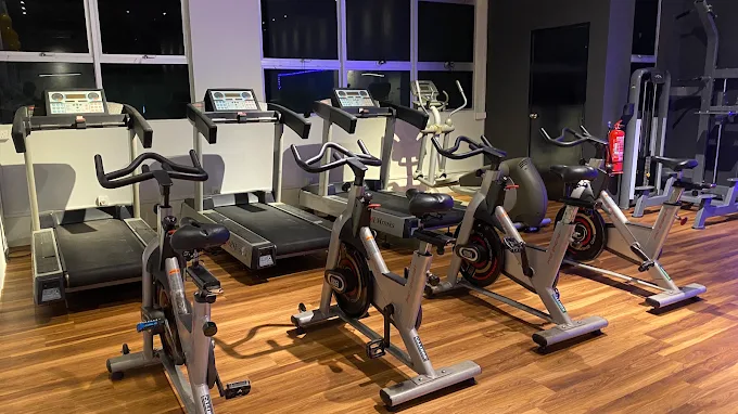 A row of treadmills and spin bikes on a wooden floor at SSF Banting.